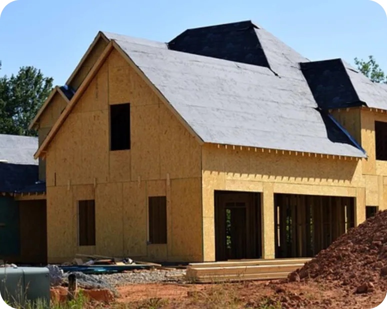 Two-story house under construction with plywood walls and black roofing.