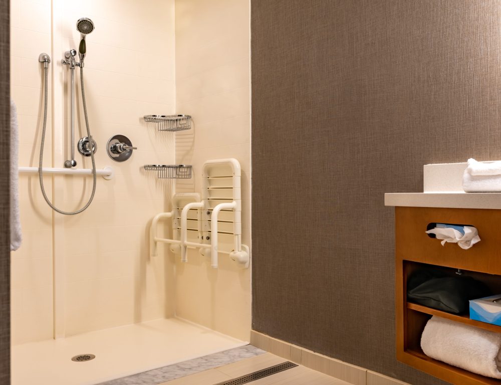 Wheelchair accessible bathroom shower with tile floor and walls.
